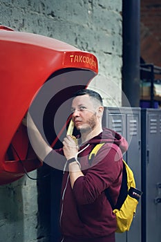 Portrait of a man calling a pay phone in a loft space. Translation: pay phone.