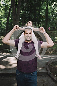 Portrait of man carrying daughter on his shoulders outdoor