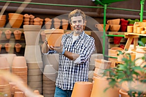 Portrait of man choosing pots for flowers and trees in gardening market