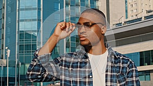 Portrait of man in city african american guy young student man in stylish sunglasses wears plaid shirt looks away to