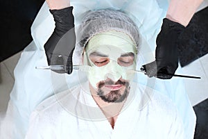 Portrait of a man with a clay face mask in a beauty salon.The concept of caring for a man& x27;s face. Men& x27;s