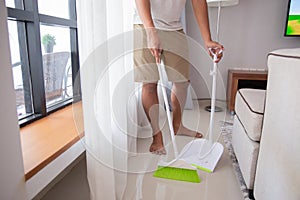 Portrait a man cleaning living room with broom