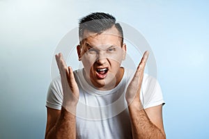 Portrait of a man close-up, experiencing anger, hate, against a light background. The concept of human emotions