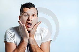 Portrait of a man close-up, who is surprised to spread his hands. On a light background. The concept of human emotions