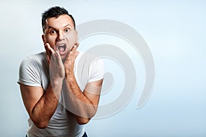 Portrait of a man close-up, who is surprised to spread his hands. On a light background. The concept of human emotions