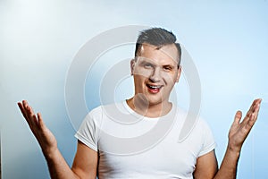 Portrait of a man close-up, who is surprised to spread his hands. On a light background. The concept of human emotions