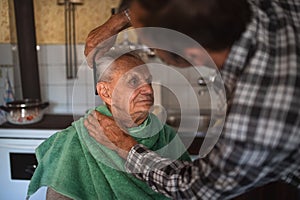 Portrait of man combing hair of elderly father indoors at home.