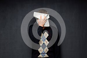 Portrait of man covering his face with paper sheet