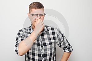 Portrait of man covering his nose with hand isolated on white studio background. Bad breath concept