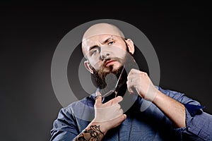 Portrait of man cutting his beard with scissors and looking at camera