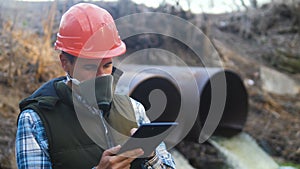 Portrait man with a digital tablet is exploring environmental pollution radiation waste. a man in a respirator mask and