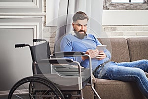 Portrait of a man with disability laying on a couch and using a tablet computer