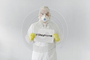 Portrait of man doctor in protective clothes during coronavirus pandemic. holding an inscription stayhome