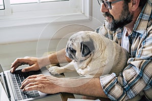 Portrait of man and dog working together at home with laptop computer - concept of free smart work lifestyle people - caucasian
