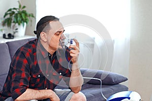 Portrait of a man doing inhalation. Use nebulizer and inhaler for the treatment