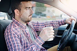 Portrait of man drinking coffee while driving car