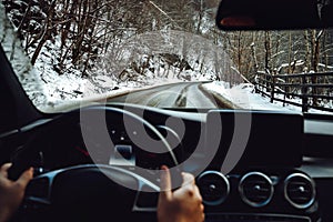 Portrait of man driving new modern car. details of winter roads and blurry dashboard