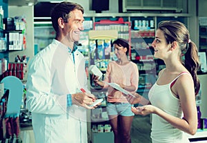 Portrait of man druggist in white coat giving advice to customer