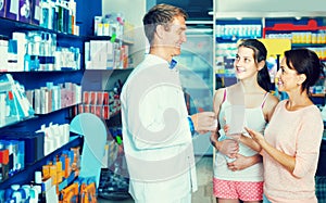 Portrait of man druggist in white coat giving advice to customer