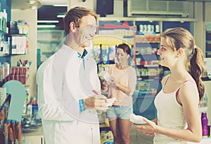 Portrait of man druggist in white coat giving advice to customer
