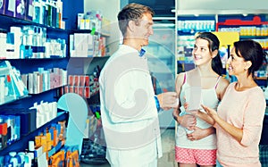 Portrait of man druggist in white coat giving advice to customer photo