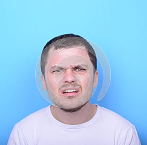 Portrait of man with dusgusted gesture against blue background