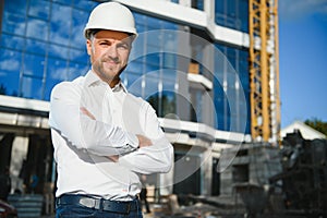 Portrait of man engineer at building site. Male construction manager wearing white helmet and yellow safety vest