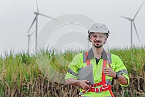 portrait man engineer worker thumbs up holding laptop at wind turbine field renewable energy. technology protect environment