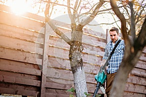 sunset portrait of man enjoying working in garden, using leaf blower and vacuum