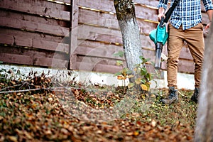 Portrait of man enjoying working in garden, using leaf blower and vacuum