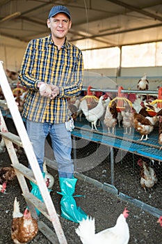 Portrait of man farmer holding eggs in hands in henhouse