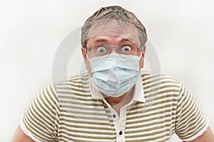 Portrait of a man fifty years in a medical mask with glasses with bulging eyes