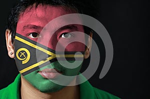 Portrait of a man with the flag of the Vanuatu painted on his face on black background.