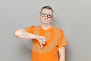 Portrait of man giving thumb down signs of disapproval and smiling