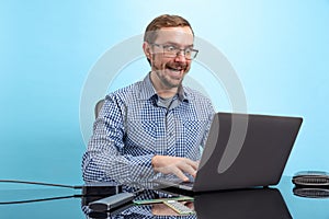 Portrait of man in glasses and checkered shirt, computer geek, programmer isolated over blue background