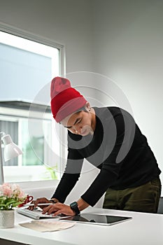 Portrait of a man graphic designer in red wool hat is planning new project on table.