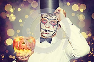 Portrait of man for Halloween party. Beautiful halloween man with burning pumpkin in hand. Halloween party concept.