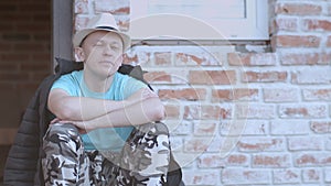 Portrait of a man in a hat and jacket, resting on the porch of a private house, copy space