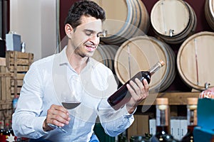 Portrait of man holding bottle and glass of wine in alcohol sec