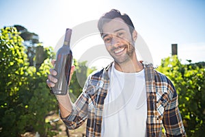 Portrait of man holding wine bottle at vineyard