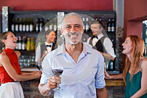 Portrait of man holding a wine glass in front of bar counter