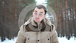 Portrait of a man in a jacket approving something by nodding his head. Man stands in winter forest.