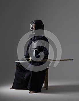 Portrait of man kendo fighter with bamboo sword in traditional uniform.