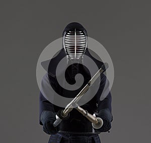 Portrait of man kendo fighter with two bamboo swords in traditional uniform