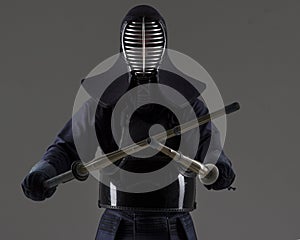 Portrait of man kendo fighter with two bamboo swords in traditional uniform