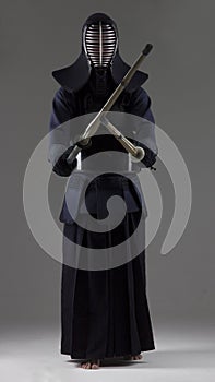 Portrait of man kendo fighter with two bamboo swords in traditional uniform.