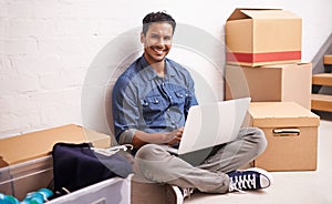 Portrait, man and laptop by boxes in new house, apartment or property for moving, relocating or buying a home. Male photo