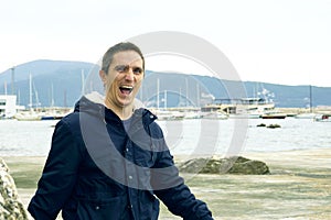 Portrait of a man laughing with delight, taken on the coast on a cloudy day.