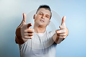 Portrait of a man on a light background close-up. Emotion importance, shows the hand gesture of the gun in the camera. The concept photo