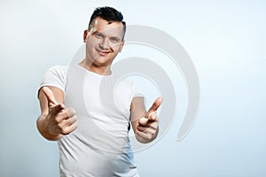 Portrait of a man on a light background close-up. Emotion importance, shows the hand gesture of the gun in the camera. The concept